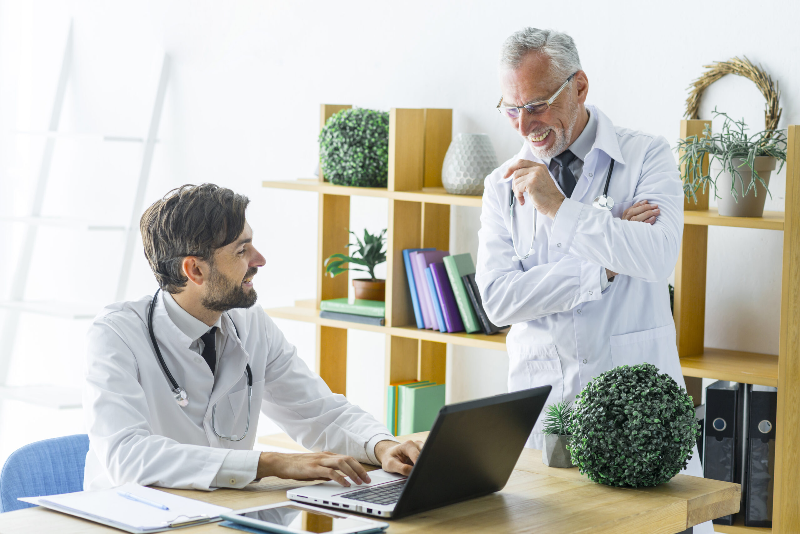 elderly doctor smiling and young colleague with laptop