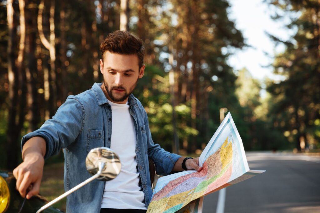 bearded man near scooter looking at map outdoors