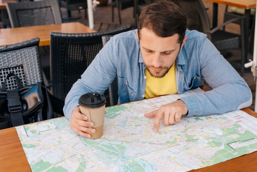handsome young man looking at a map while holding a coffee cup