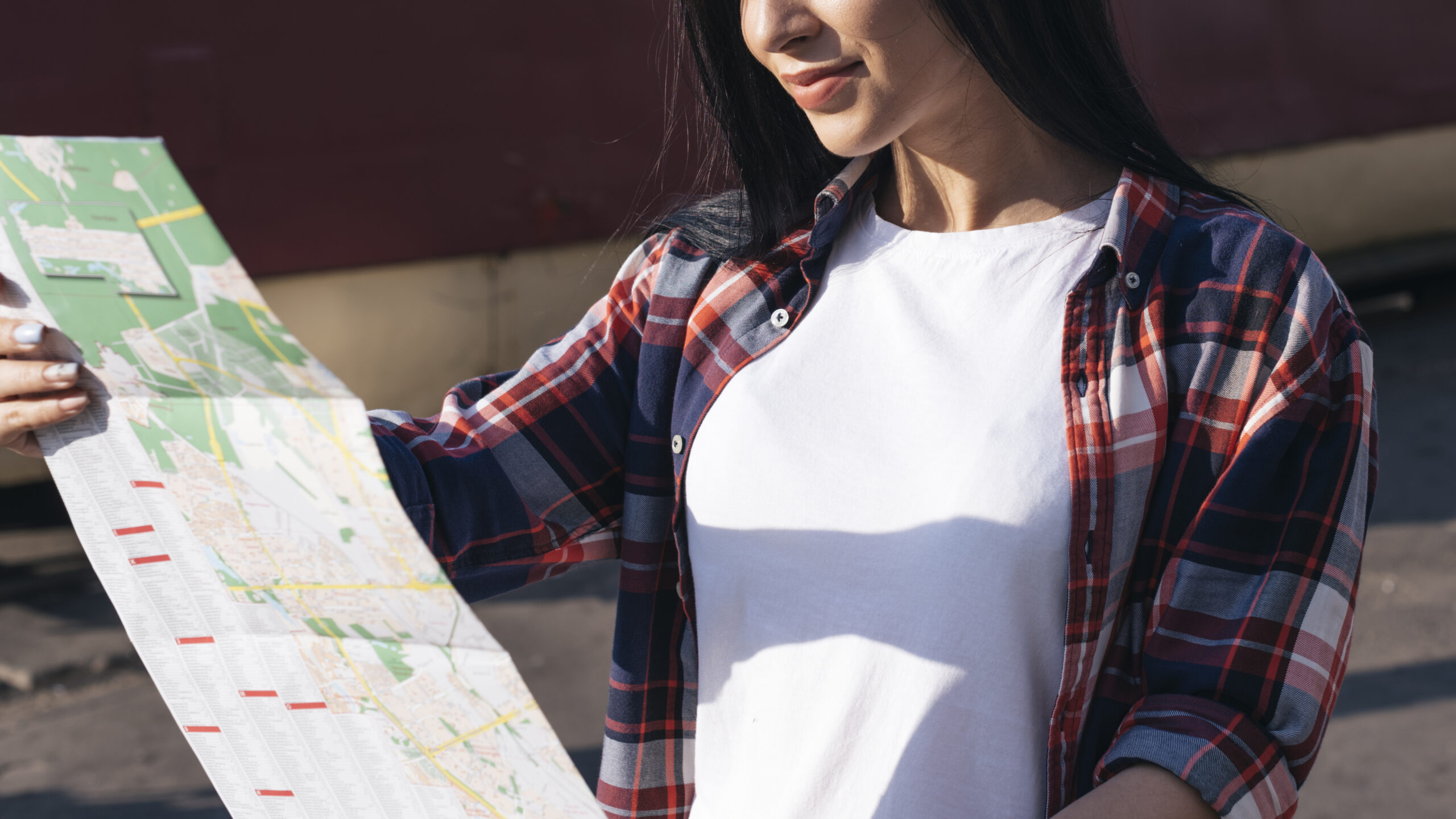 Close-up of a happy woman reading a map outdoors